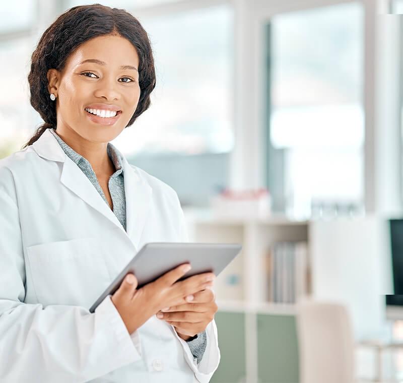 A clinical medical professional in scrubs takes a patient’s blood pressure in a well-lit exam room, demonstrating care and precision during a routine health check.